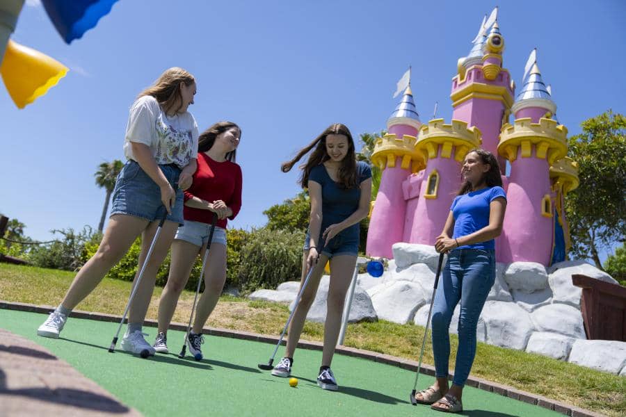 Four girls play mini golf.